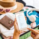 Woman reading packing list on phone while packing suitcase