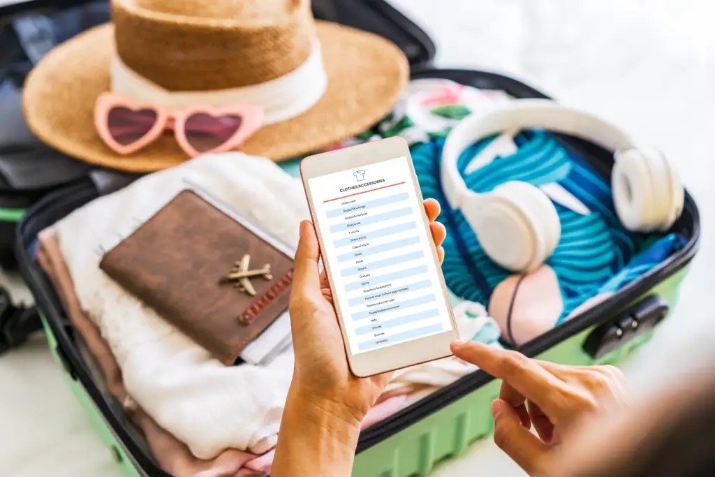 Woman reading packing list on phone while packing suitcase