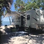 A cozy interior of a rental travel trailer with a comfortable bed and warm lighting, perfect for a relaxing road trip.