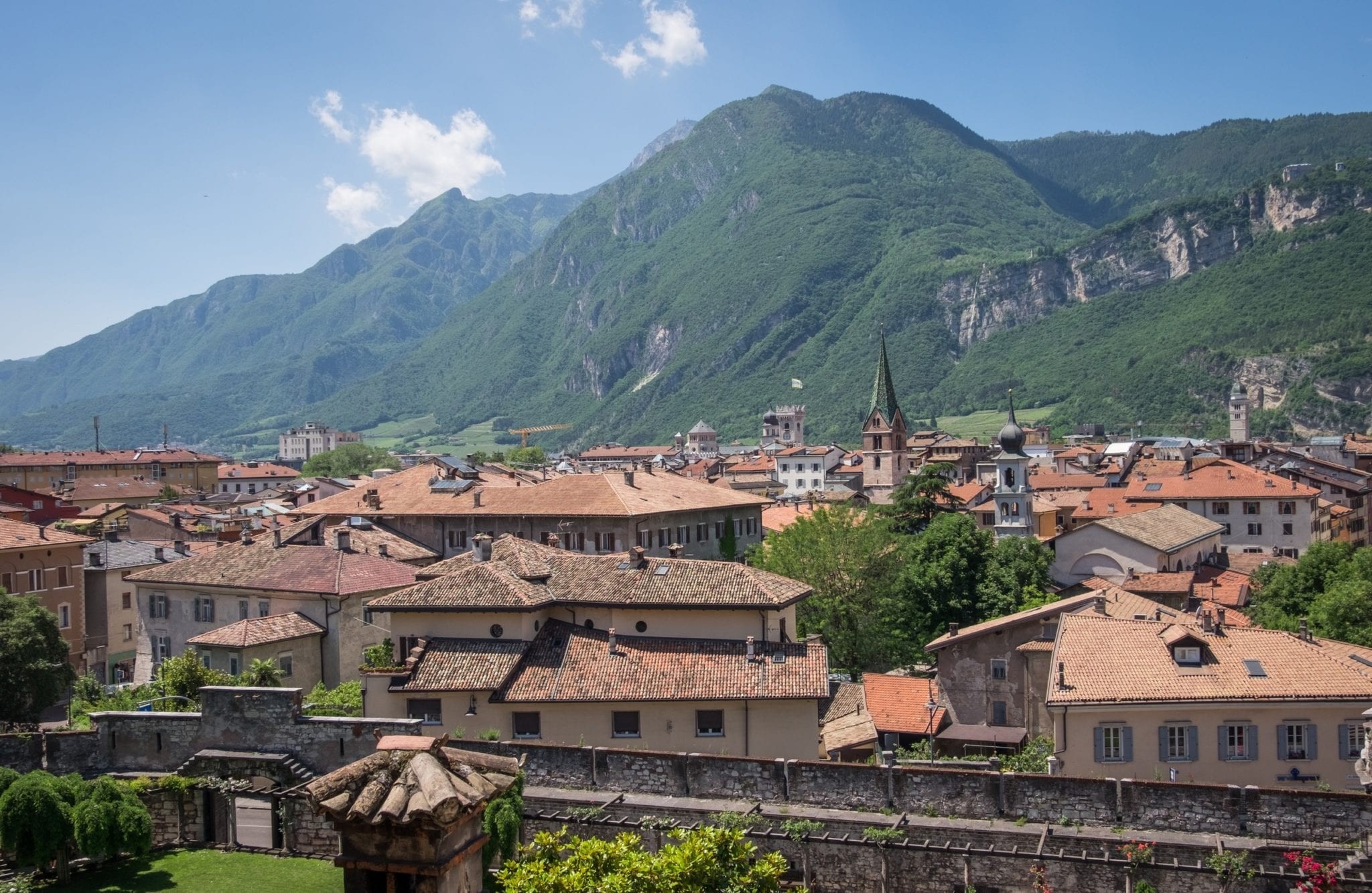 The terra cotta roofs of Trento, Italy with mountains in the background.