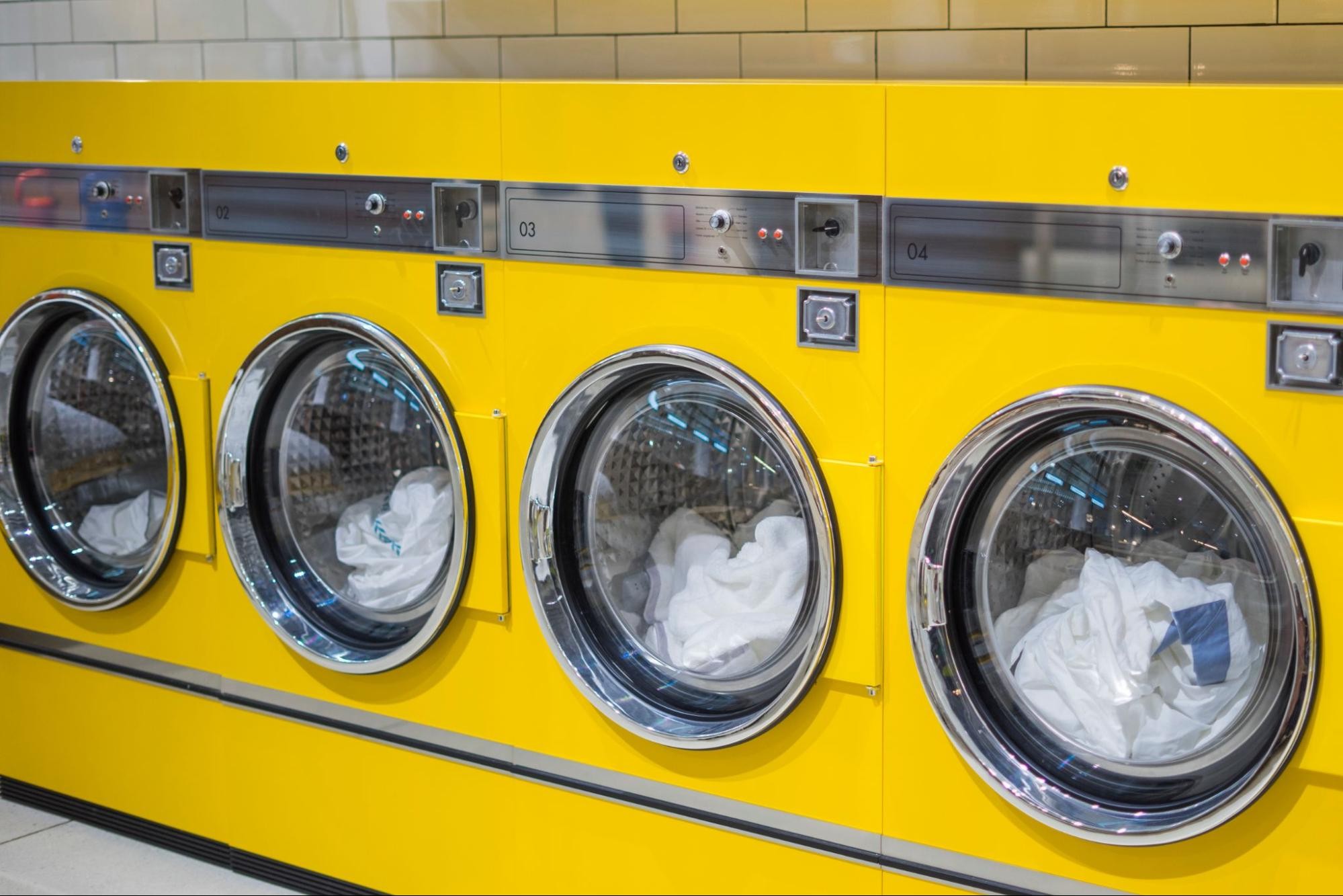 A laundromat with yellow coin-operated washing machines