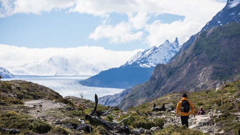 Trekker in Patagonia, Chile, wearing a yellow jacket. &quot;Alt text: Lone trekker braving the Patagonian wilderness in vibrant yellow jacket, emphasizing the resilience needed to explore this dynamic landscape during the shoulder seasons.&quot;