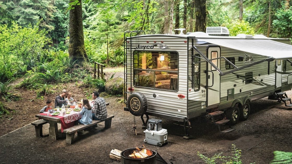 Image of a Jayco travel trailer with a family enjoying the outdoors, emphasizing the peace of mind that comes with the brand's warranty