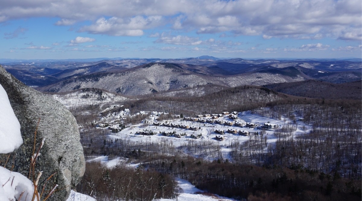 A snowy view of the town of Killington, Vermont, nestled among hills and trees.