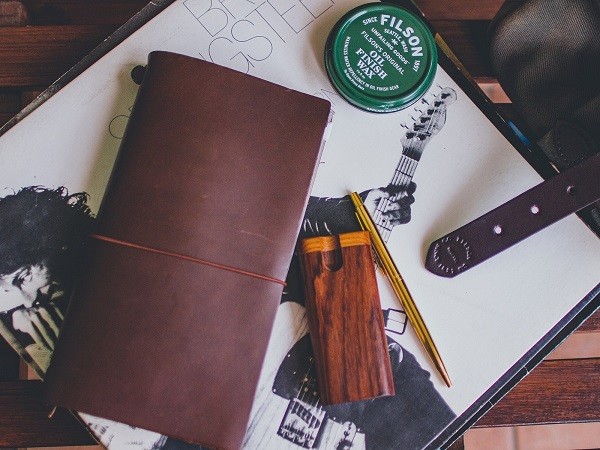 Traveler's Notebook being used as a day planner with various inserts and accessories, highlighting its versatility and functionality for organizing daily tasks and schedules