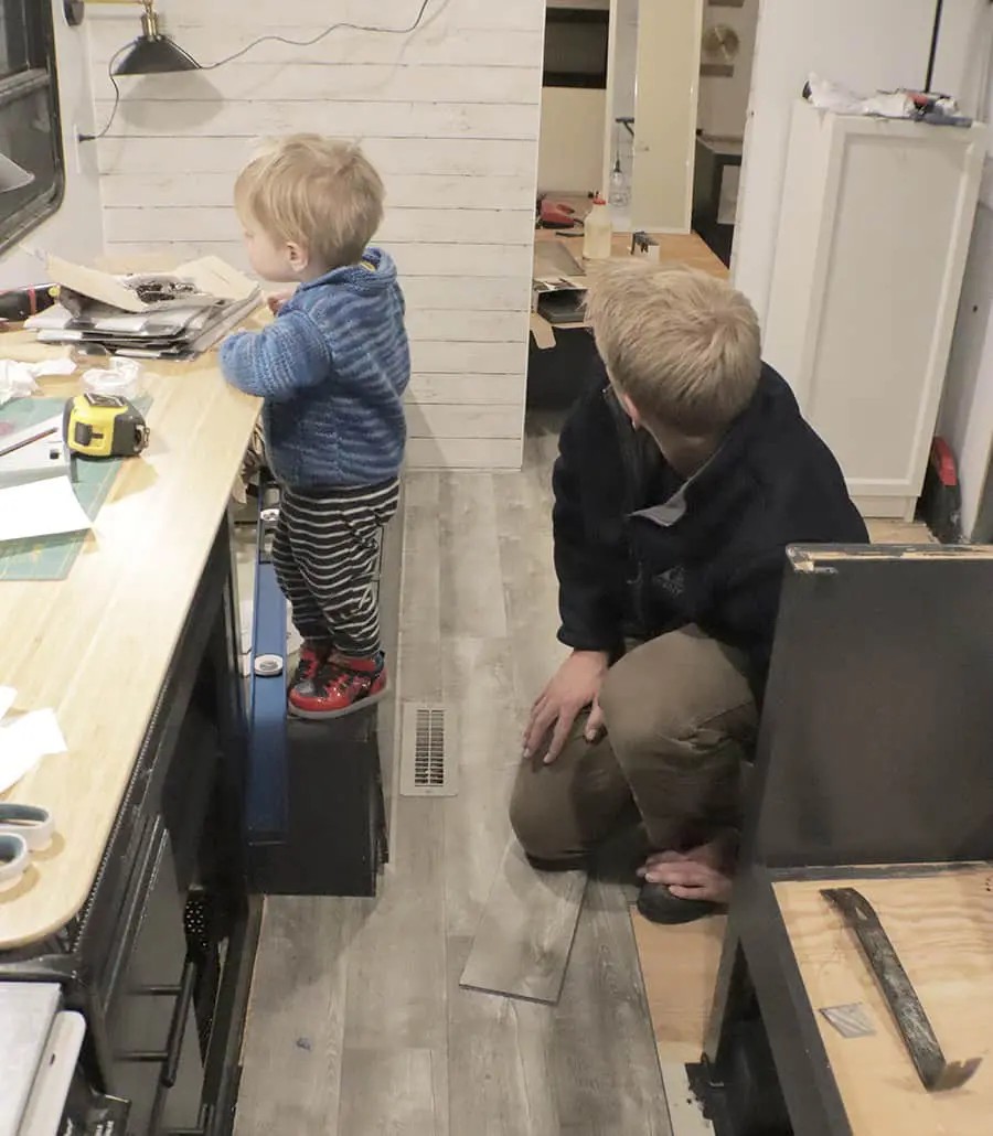 Installing new vinyl flooring in a travel trailer, showing the process of cutting and adhering the material