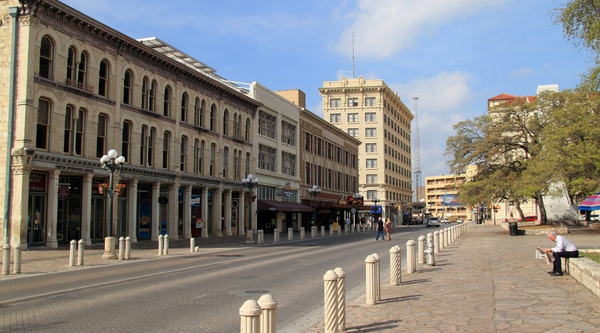 A street scene in San Antonio, Texas, on a sunny day, showing pedestrians and historic buildings.