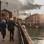 An elderly couple walks at sunset on a bridge in Venice, Veneto, Italy