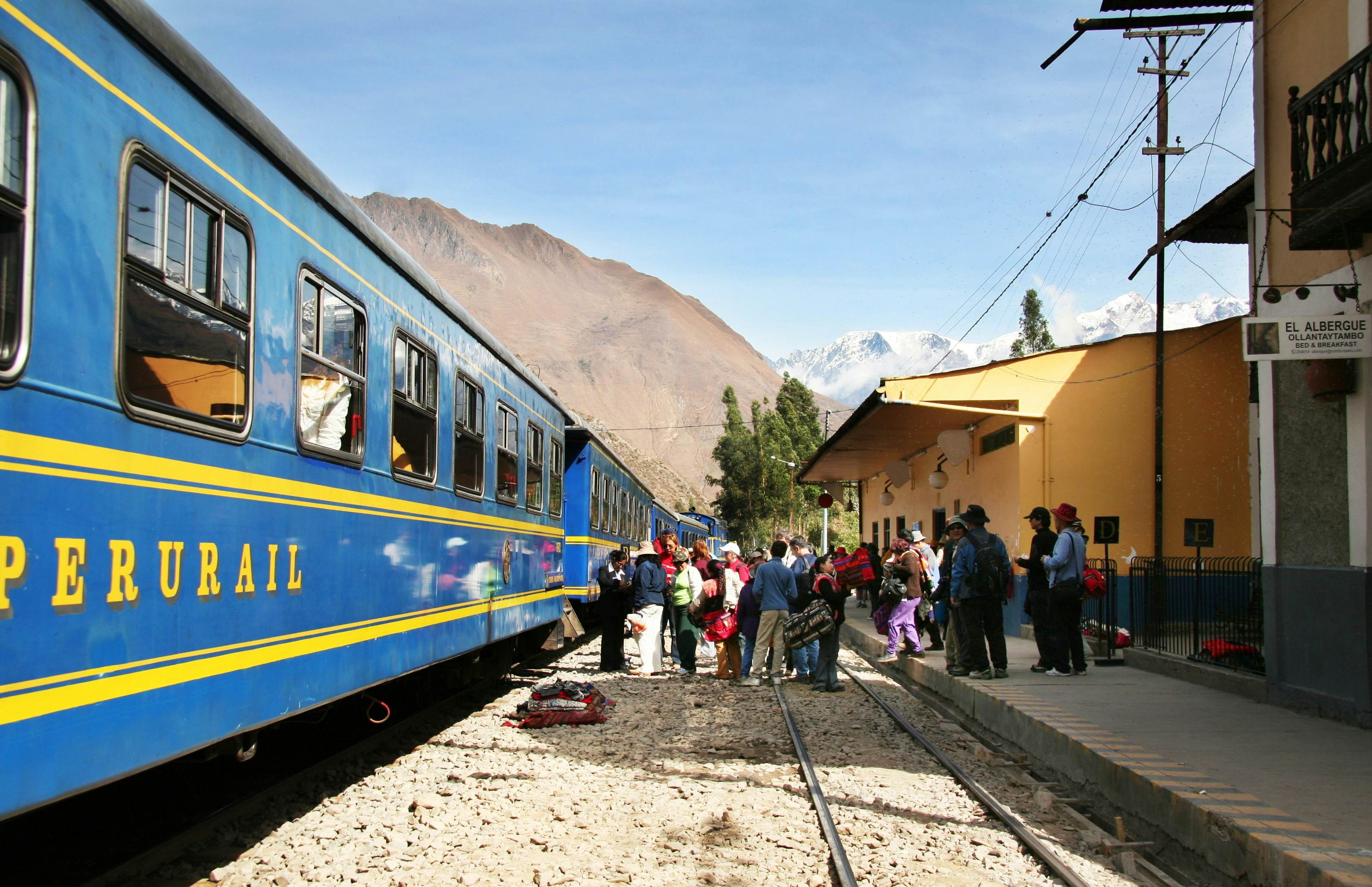 People line up to board a blue train in Machu Picchu, highlighting scenic train journeys in Peru.
