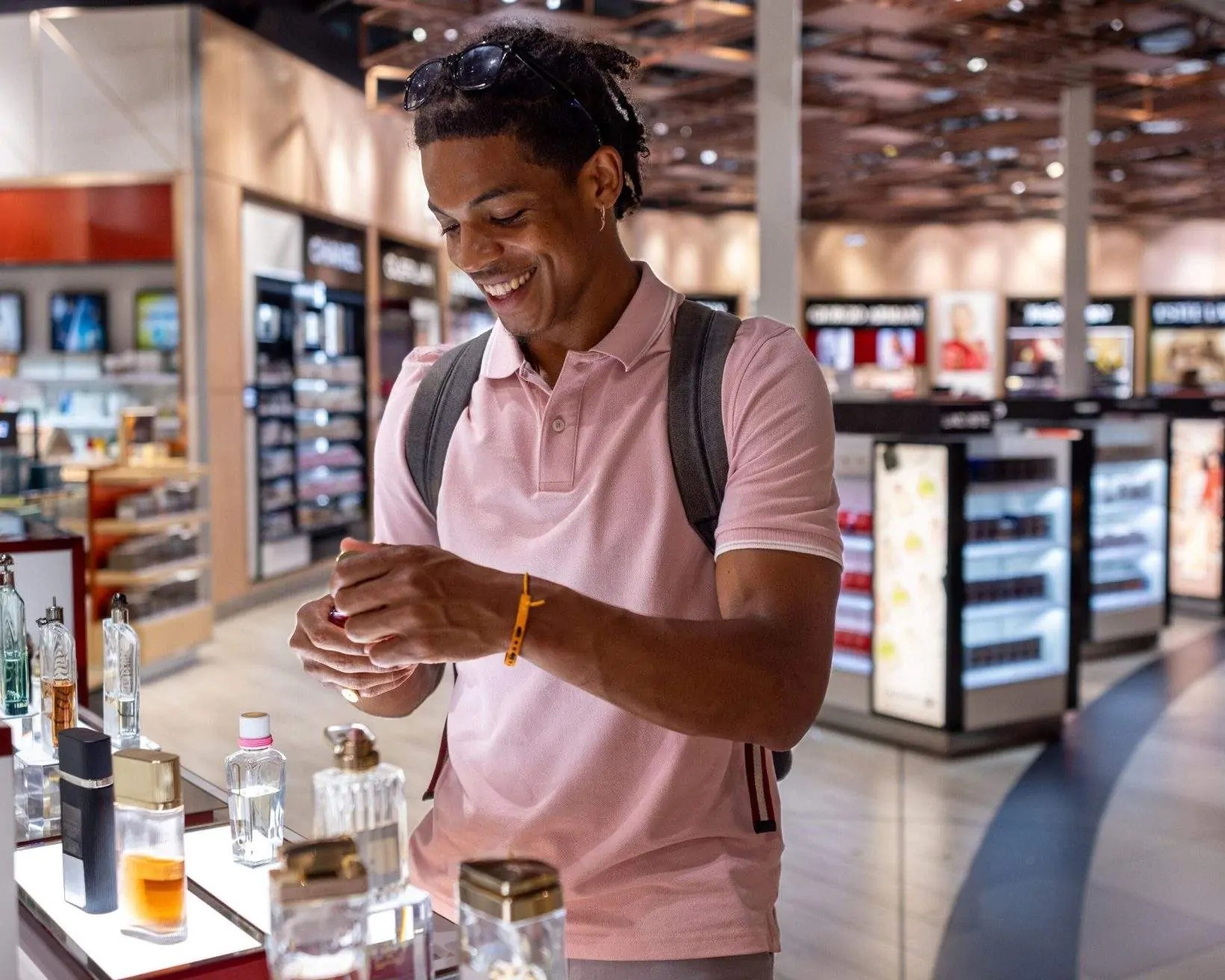 Man smelling aftershave in a duty-free shop, illustrating airport shopping