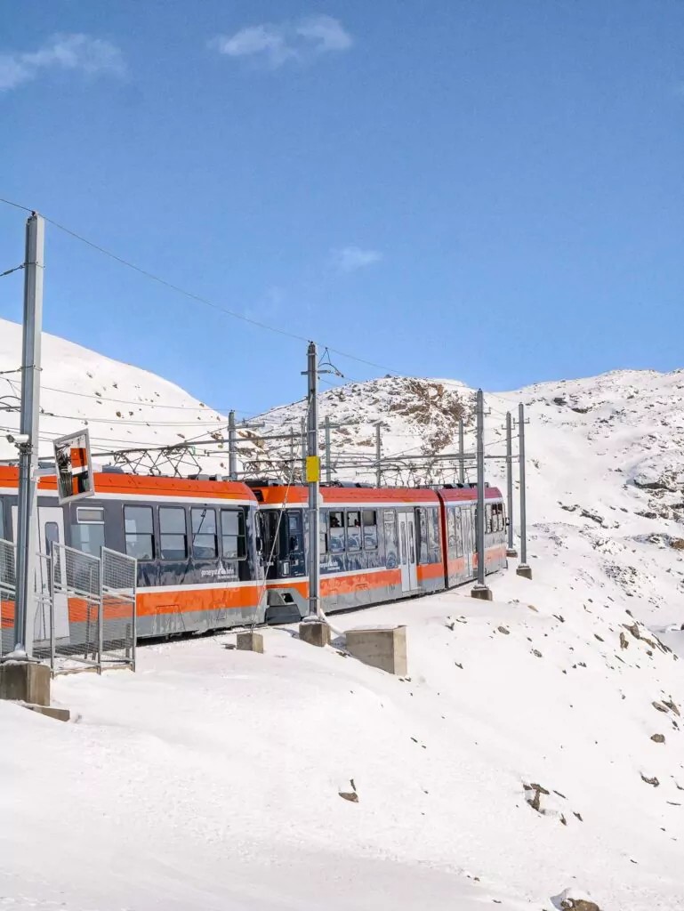 A vibrant red and white train winding through a snow-covered mountain landscape, offering a glimpse into the unforgettable experiences awaiting travelers on a ten day Switzerland itinerary
