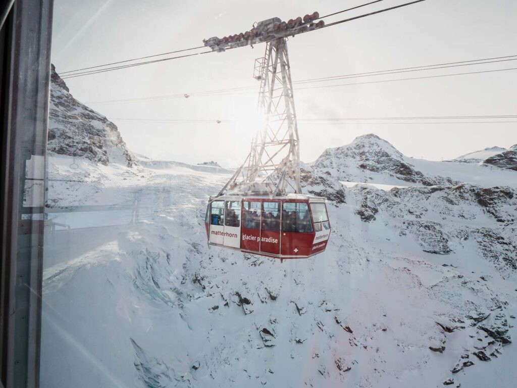 A scenic view from inside a moving train, showcasing the Swiss Alps under a clear blue sky, capturing the essence of scenic train journeys in Switzerland