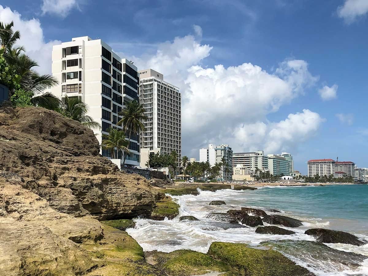 Waves crashing on rocks with buildings in the background
