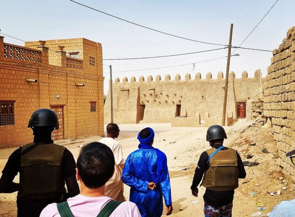 Soldiers in Timbuktu escorting visitors, emphasizing the ongoing need for security measures in the city to protect tourists.