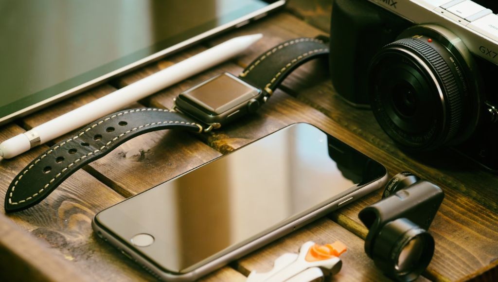 Accessories including a phone, watch, and camera on a crate