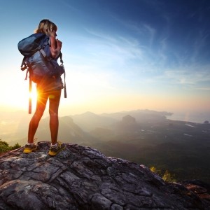 Backpacker enjoying a mountain sunrise with a large backpack