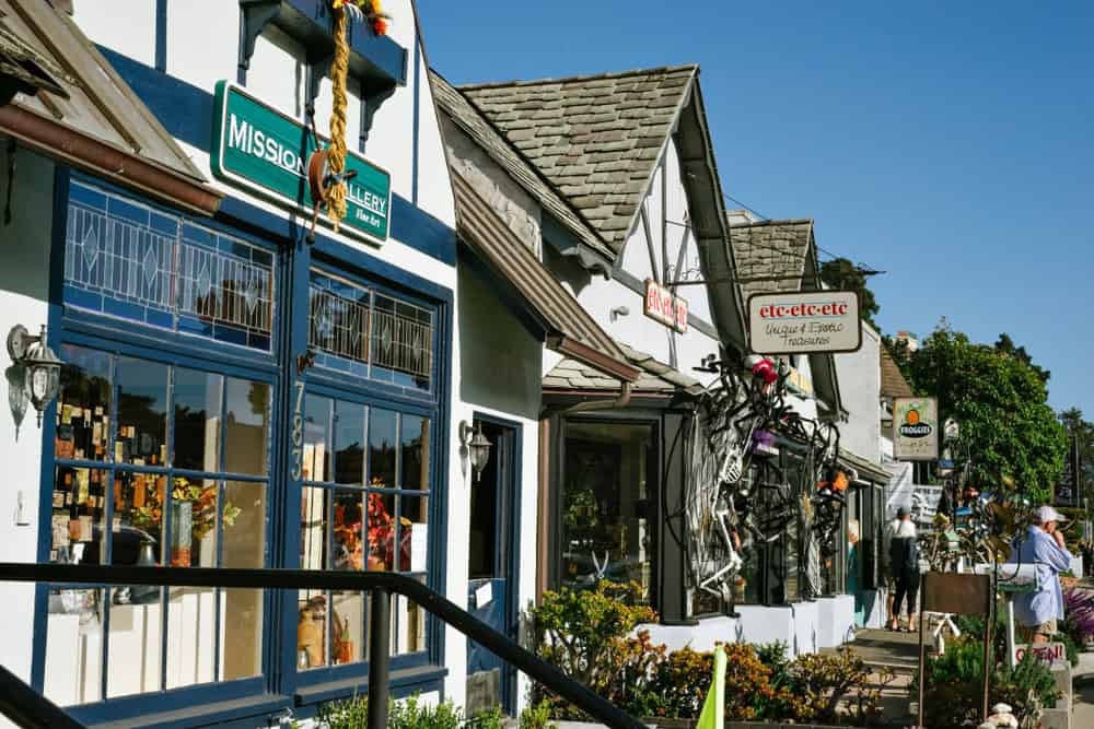 Shops line the street in Cambria showing the quaint downtown with flowers and unique storefronts.
