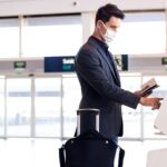 Man at the airport wearing a face mask and holding his passport.