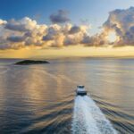 Ferry sailing across the sea with islands and sunset in the background