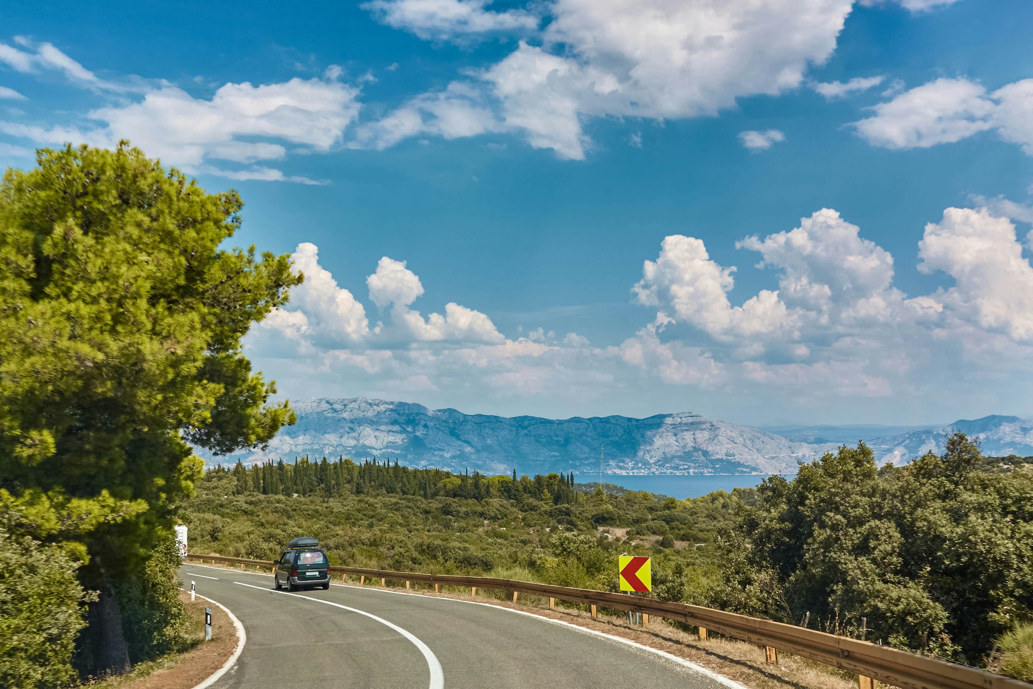 Car driving along coastal road with island scenery