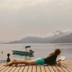 Woman reading a book on a dock by a lake
