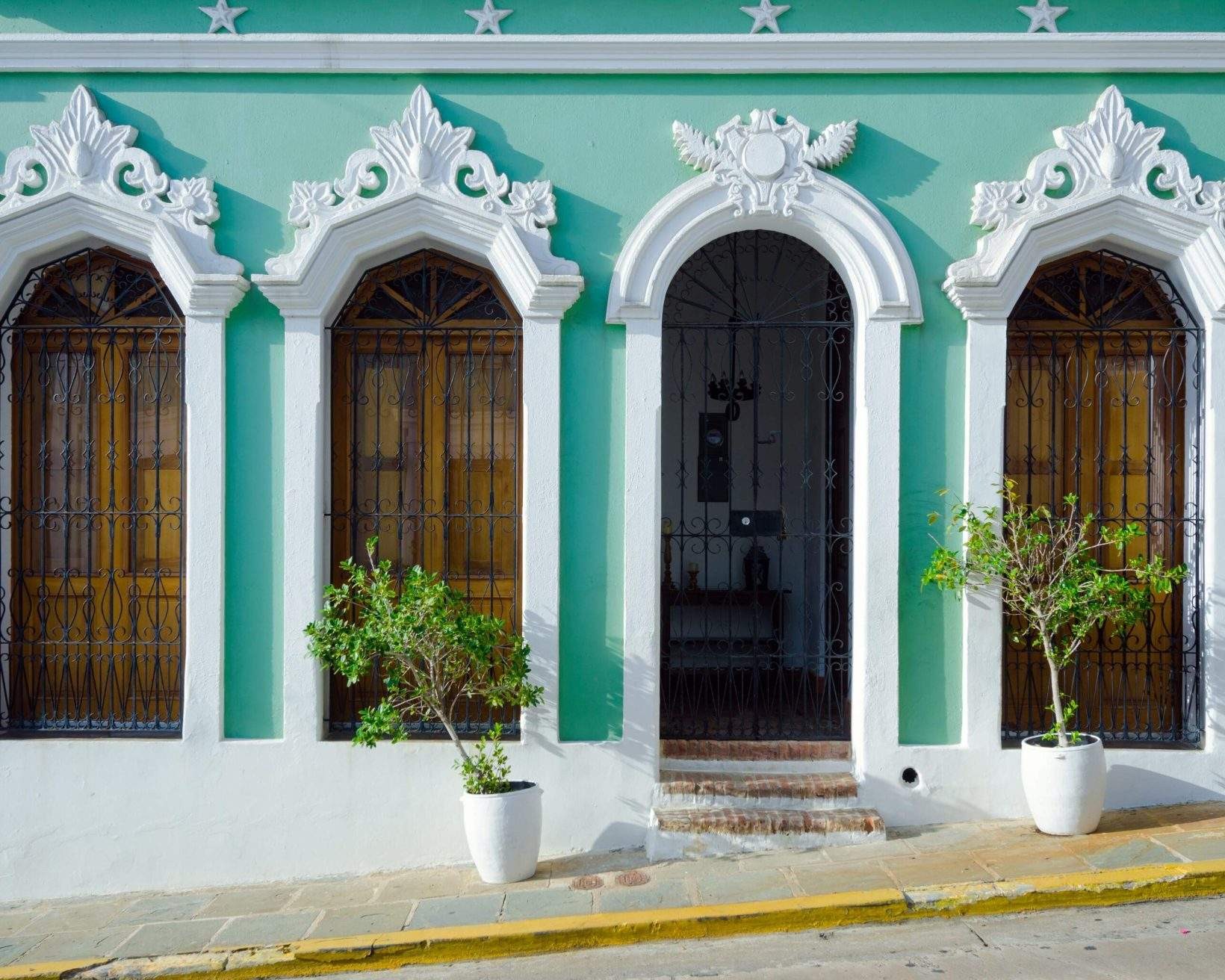 A building with light green exterior walls and white arched mouldings around its windows and doorway, showcasing the vibrant architecture of Old San Juan