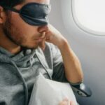 Man wearing an eye mask resting on the plane