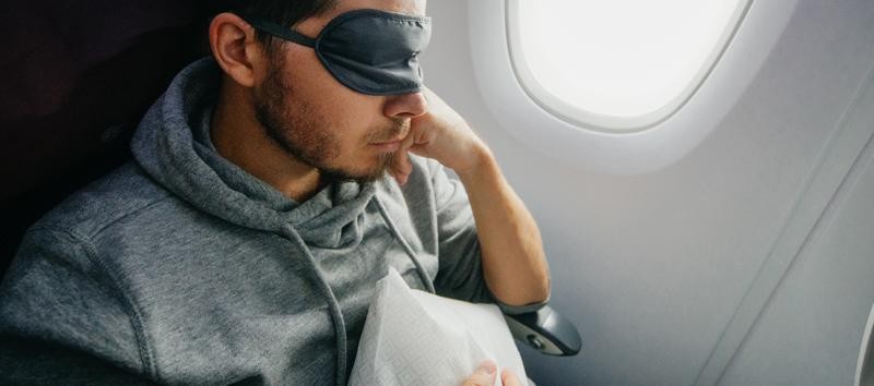 Man wearing an eye mask resting on the plane