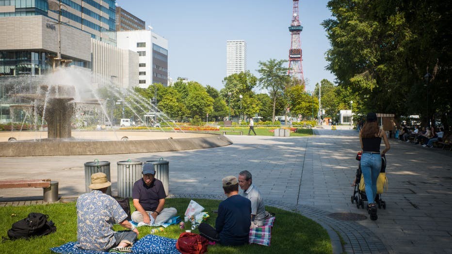 People sitting on the grass at Sapporo Odori Park in Sapporo, Japan, enjoying the vibrant green space