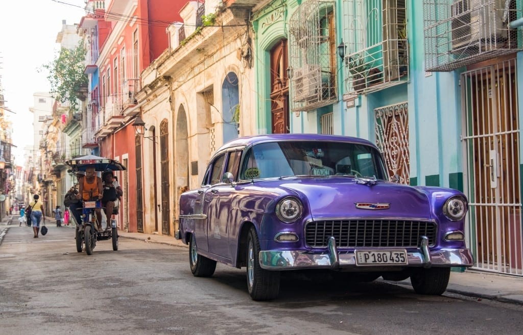 A vibrant street in Havana with classic cars and colorful buildings.