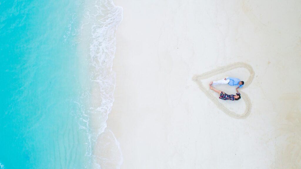 Couple sitting on a beach inside a sand heart