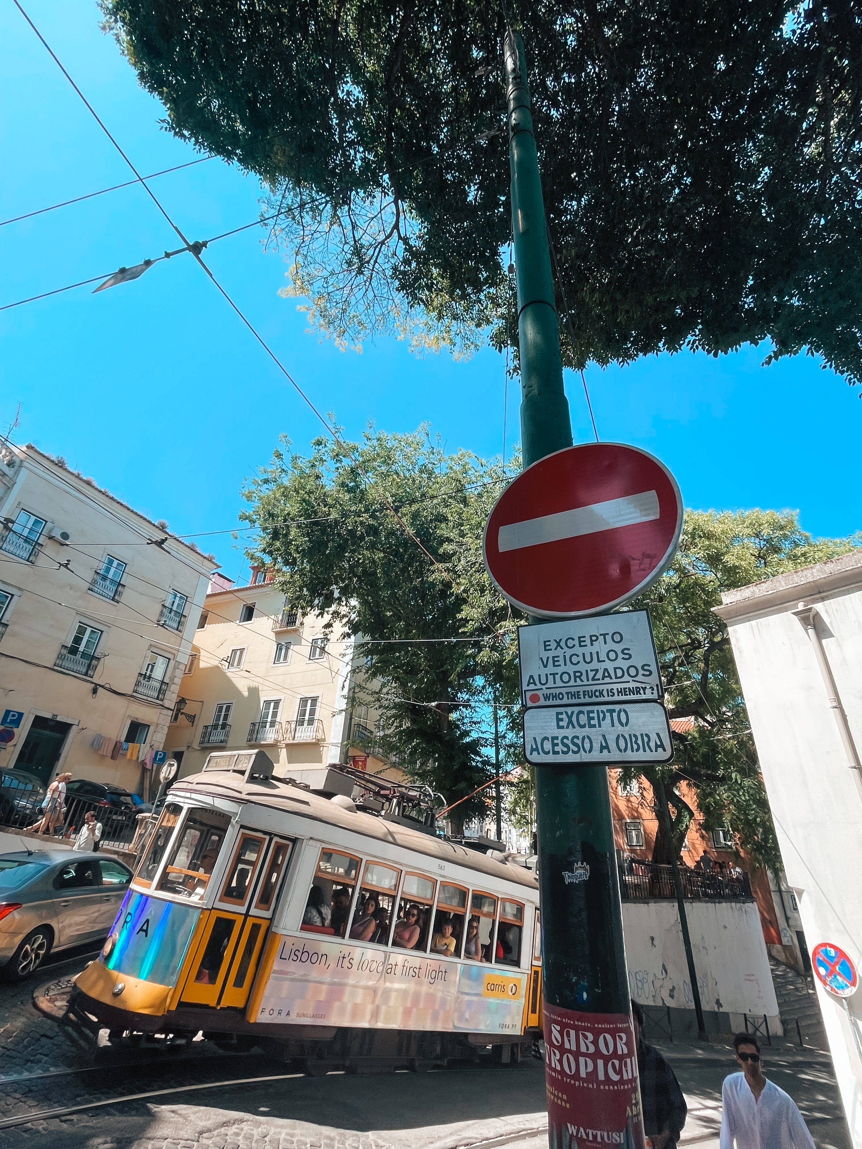 A vibrant yellow tram moving through Lisbon's narrow streets, a signature sight of the city