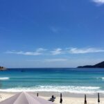 A person working remotely from a laptop on a sunny beach, showcasing the flexibility of remote work and travel.