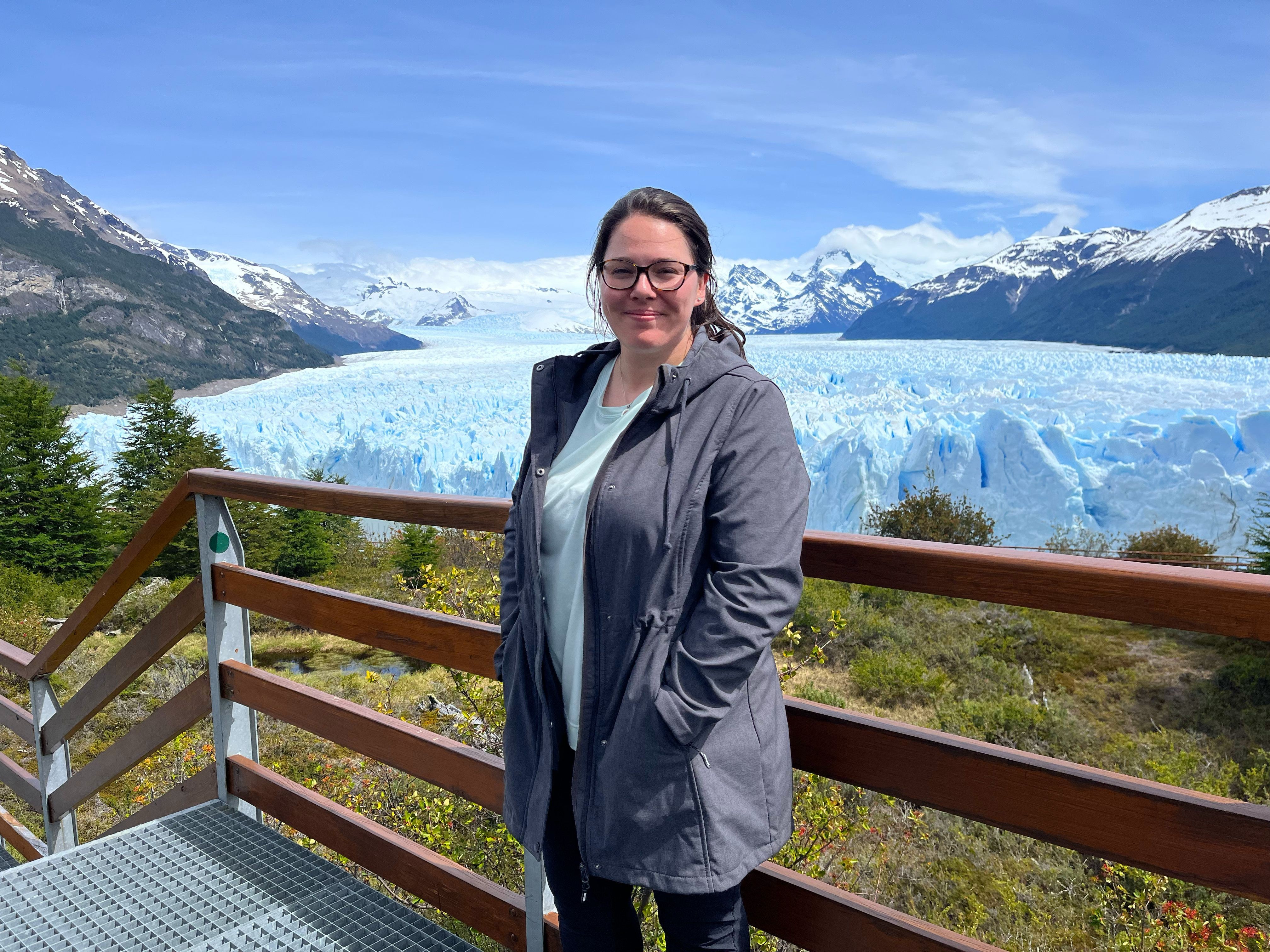 Perito Moreno Glacier towering majestically, reflecting in the turquoise water, surrounded by snow-capped mountains and clear blue skies, capturing the grandeur and serene beauty of Los Glaciares National Park.