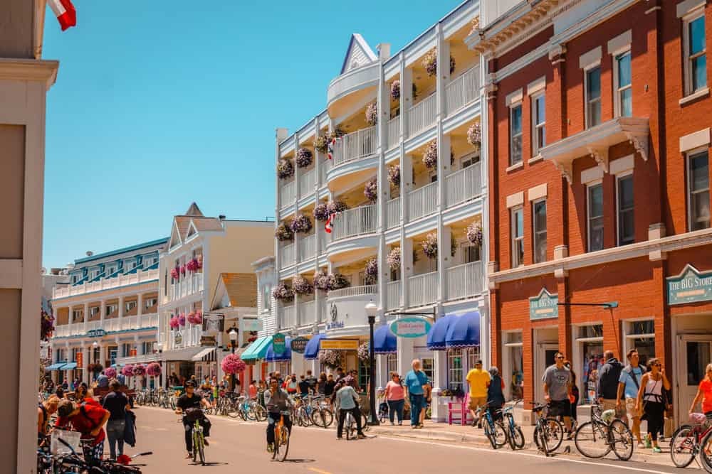 Horse-drawn carriages line a street in Mackinac Island showing the historic mode of transport and Victorian architecture.