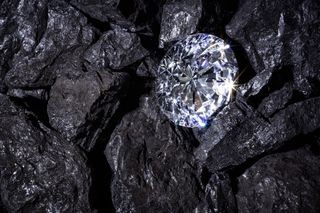 A sparkling diamond amongst dark coal-like rock.