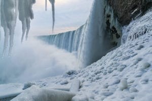 Niagara Falls in Ontario, showcasing the partially frozen falls illuminated with colorful lights during the Winter Festival of Lights.