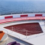 cruise ship deck with a red relaxation net and orange and purple loungers