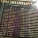 A terminal departure board displays upcoming Lufthansa flights to various European cities, detailing flight numbers and times.