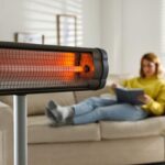 Woman reading book in living room with electric infrared heater, illustrating the conversion of electrical energy to radiant heat.