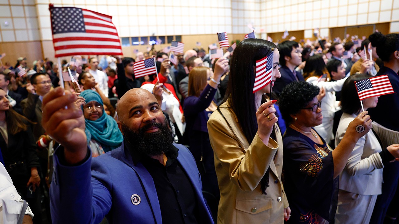 Family waving American flags at a naturalization ceremony