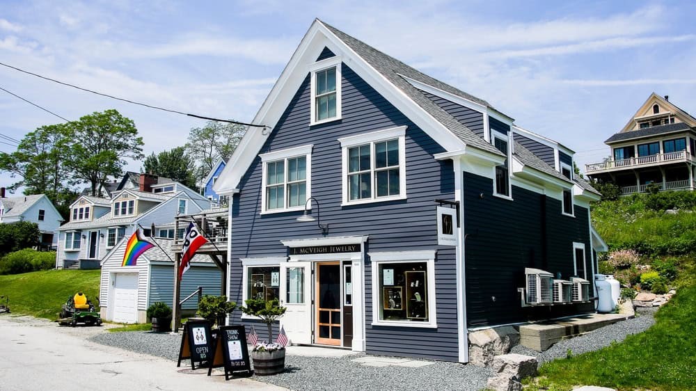 A harbor in Stonington shows colorful boats docked in the calm waters with historic buildings in the background.