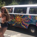 A girl smiling in front of a hippie van in California