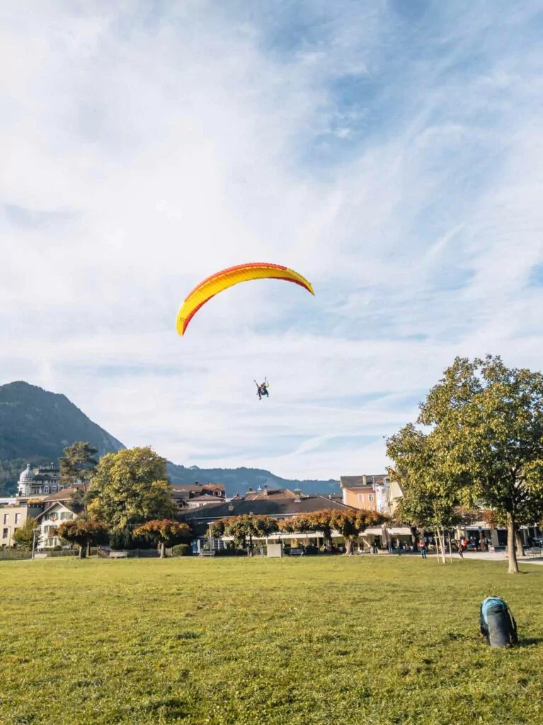 A paraglider gracefully descends onto a green field in Interlaken, Switzerland, highlighting the adventurous spirit of a ten-day Swiss adventure