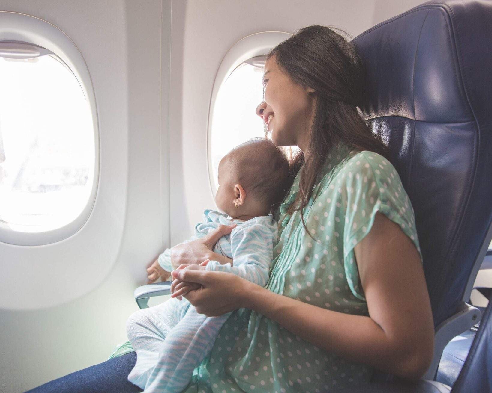 Mother and child on an airplane next to a window.