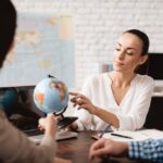 Travel advisor discussing travel plans with a client using a globe as a visual aid.
