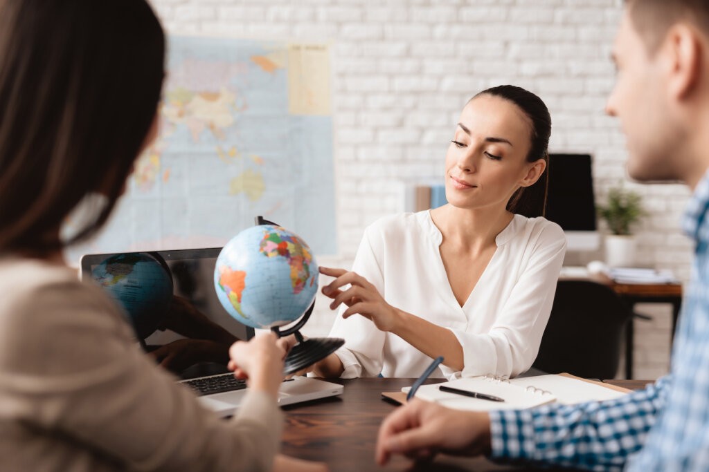Travel advisor discussing travel plans with a client using a globe as a visual aid.