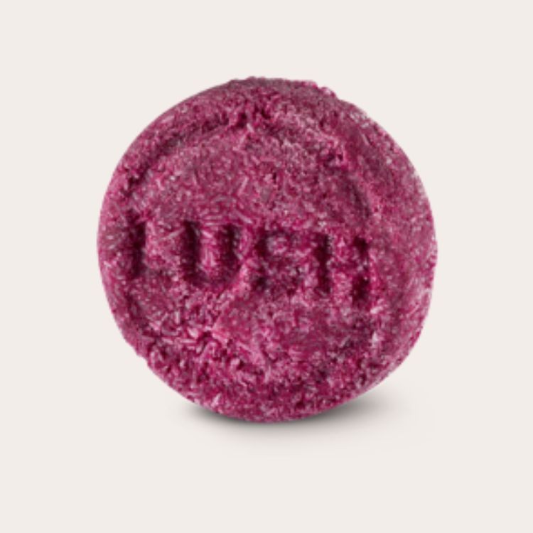 Selection of solid beauty products including a shampoo bar, foundation stick, solid perfume, and cleansing bar, emphasizing the benefits of solid alternatives for travel