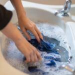 Woman carefully hand washing clothes in a hotel sink while traveling