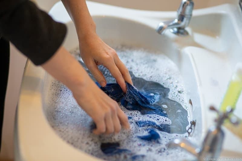 Woman carefully hand washing clothes in a hotel sink while traveling